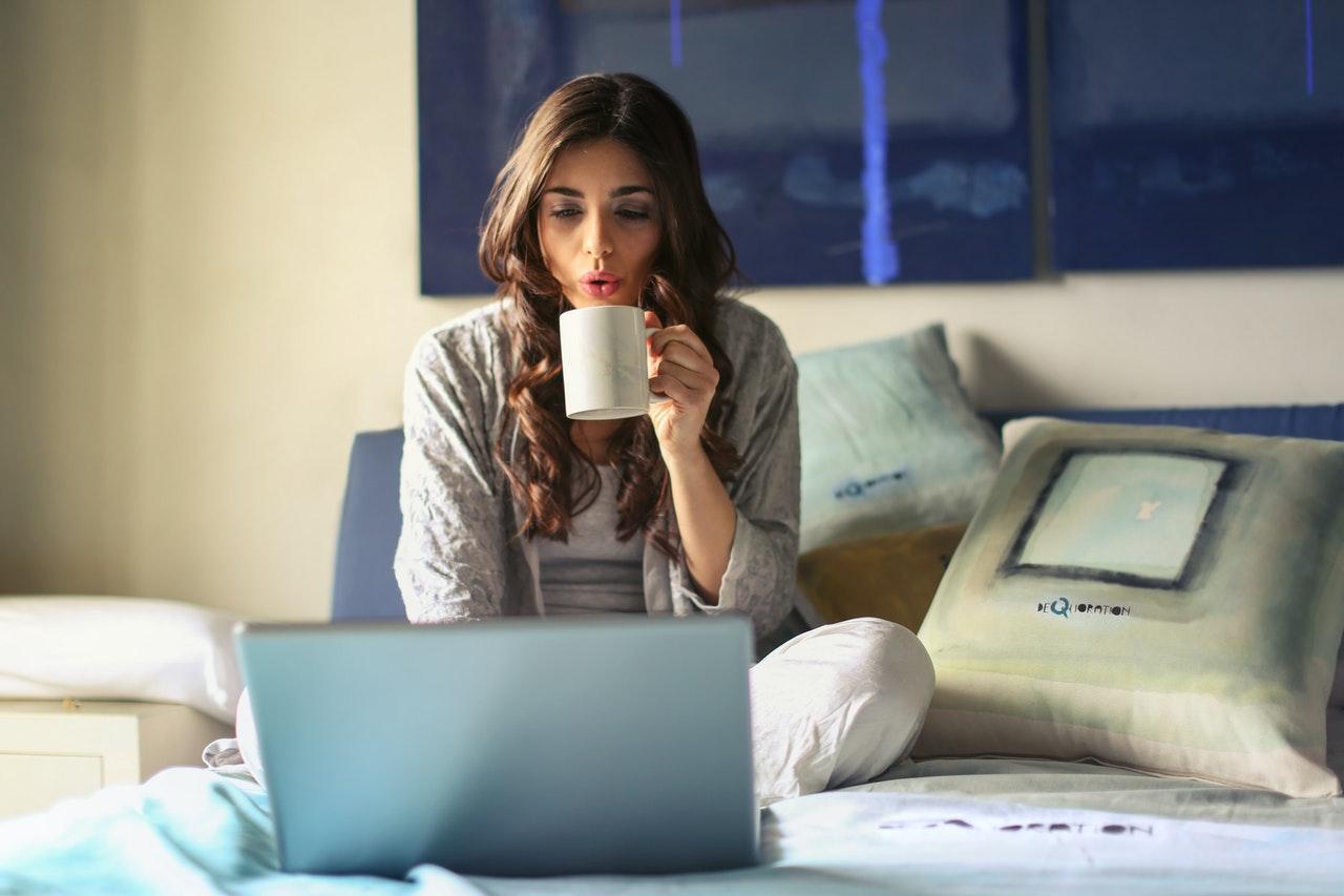 Frau mit Tasse in der Hand am Laptop